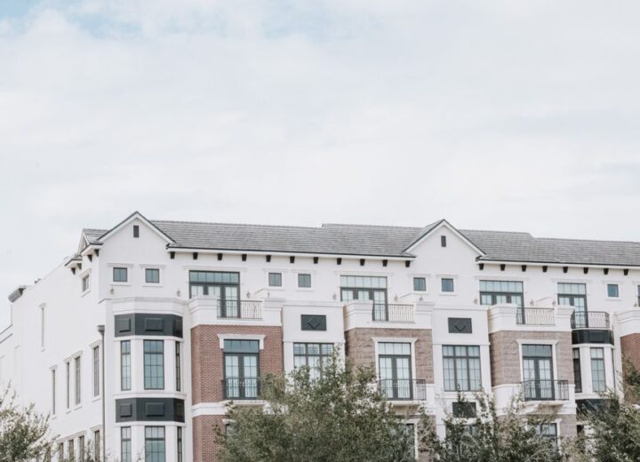 A stylish, multi-story luxury apartment building with a contemporary facade against a clear sky.