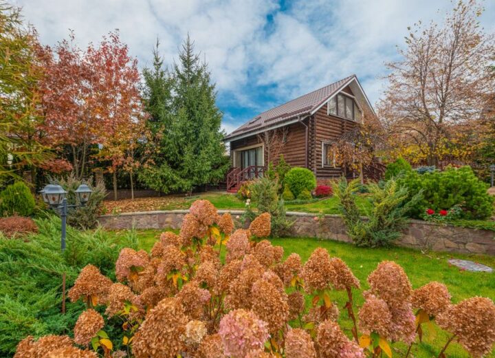 A picturesque log cabin surrounded by vibrant autumn foliage in a scenic garden setting.