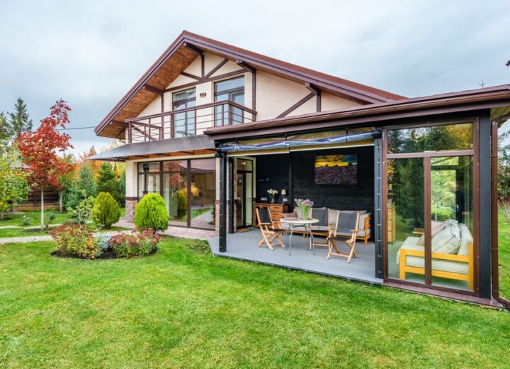 Residential cottage with balcony and opened veranda opening view on lawn and trees growing in backyard