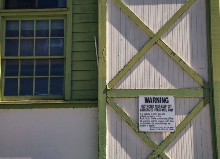 Close-up of a vintage building featuring a warning sign and green trim, emphasizing restricted access.