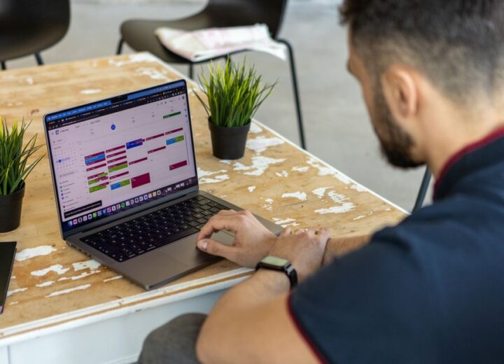 Man working remotely at a desk with a laptop open to a calendar app.