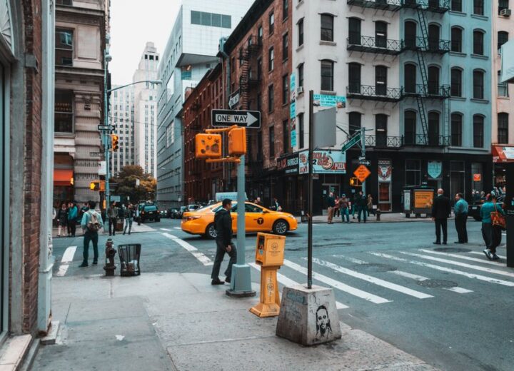 Busy city intersection with yellow taxi and pedestrians in daylight.