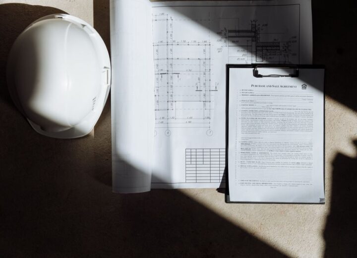 Top view of construction documents and hard hat in sunlight, capturing planning essence.