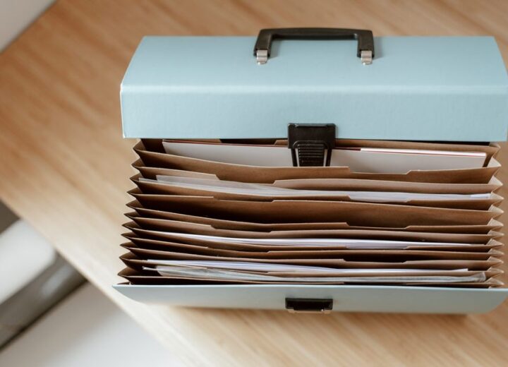 From above of briefcase for documents with papers placed on wooden table in daytime