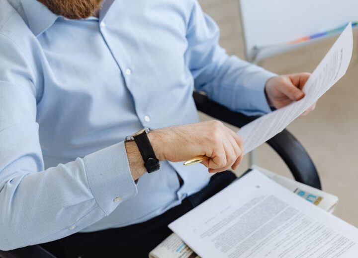 Businessman reviewing papers in office setting, highlighting analysis and attention to detail.
