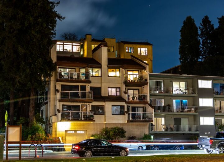 Light streaks from traffic and lit apartments capture a lively urban scene at night.