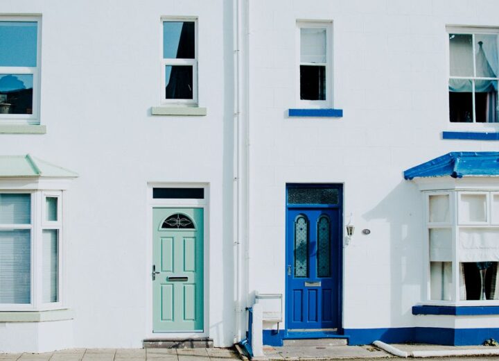 A modern exterior featuring a contrast of blue and green doors on a white building facade.