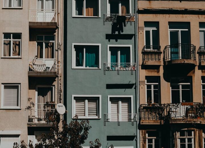 A row of urban apartment buildings with balconies and varied facades basking in sunlight, showcasing city architecture.