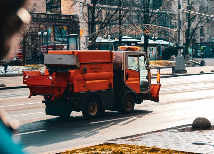 Orange street sweeper cleaning the street in Kyiv, Ukraine during daytime.