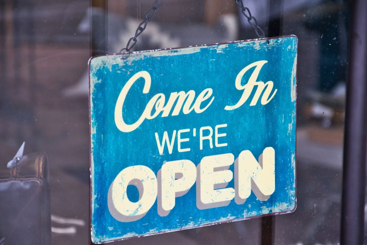 A retro open sign hanging on a shop door