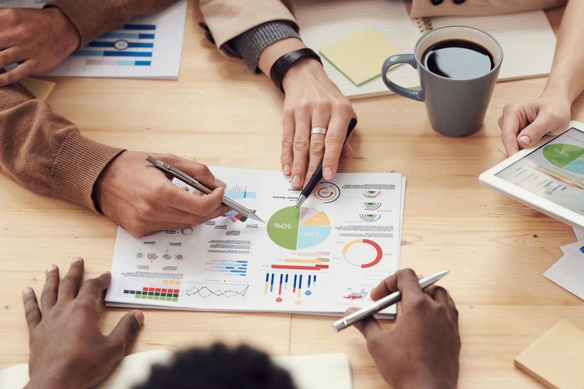 Hands and pens over printed charts on a table