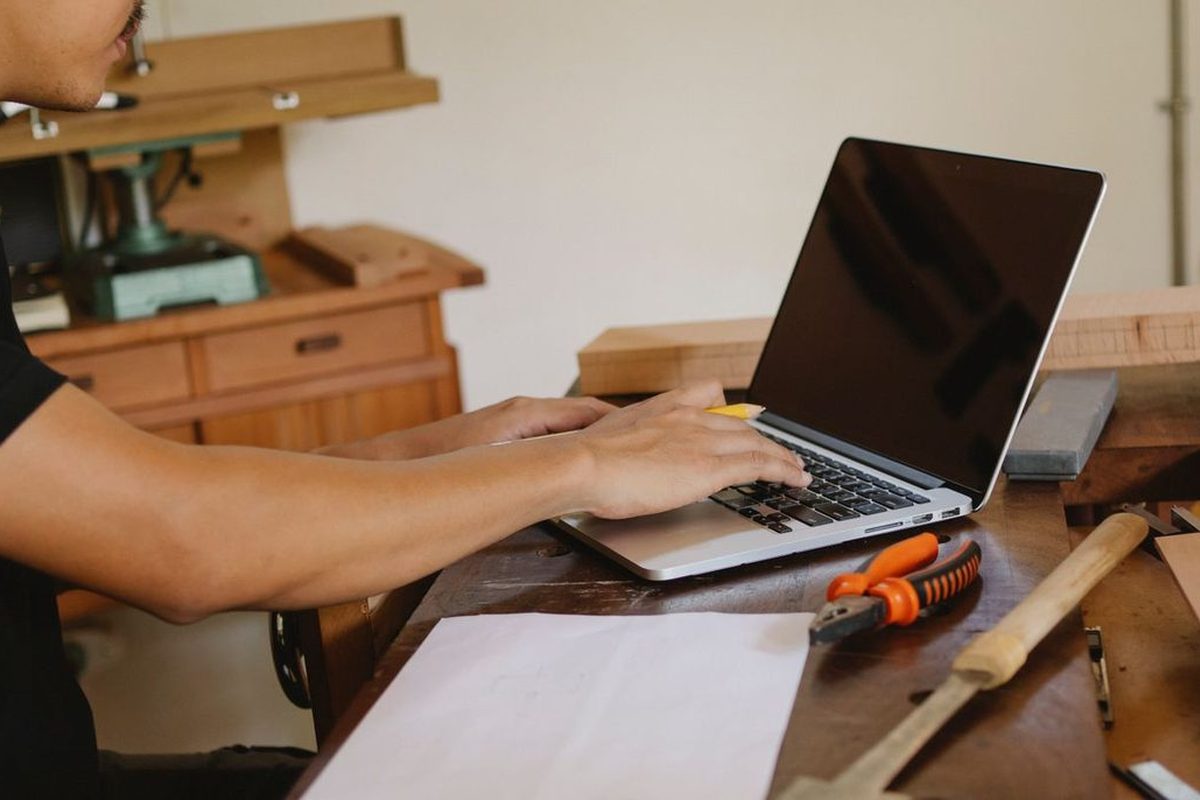 Someone working on a laptop at a workbench