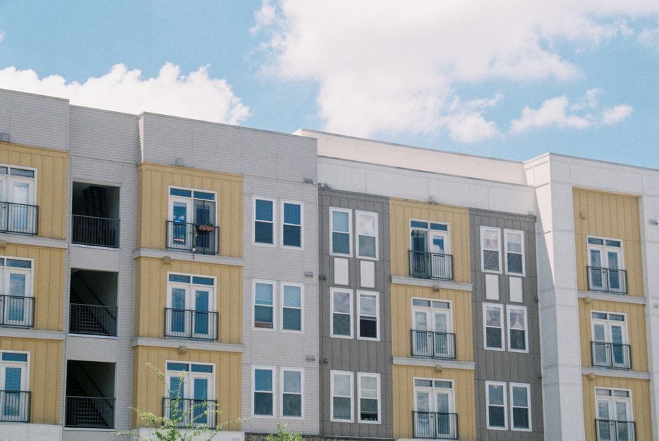 A four-storey apartment building with balconies under a blue sky