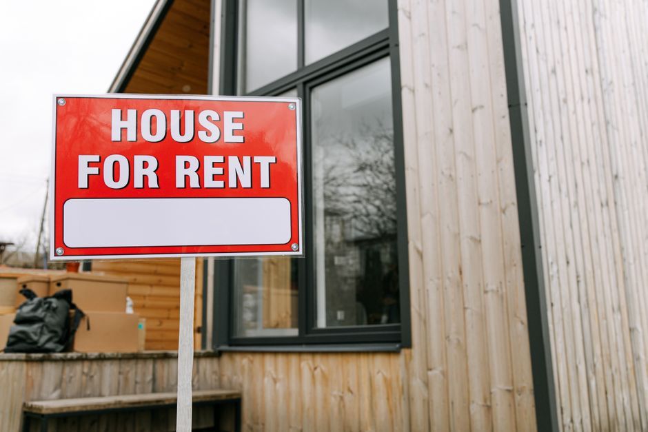 A House for Rent sign outside a wooden house